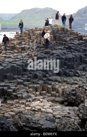 Touristen Wandern rund um die roten Basalt sechseckigen Felsformationen am Giants Causeway Grafschaft Antrim Nordirland Vereinigtes Königreich Stockfoto