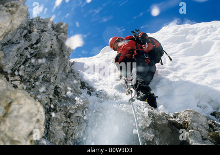 Weibliche Bergsteiger klettern über eine Wechte auf einem Stahlseil, Schnee gleiten und herunterfallen, Northern Range, Innsbrucker Kle Stockfoto