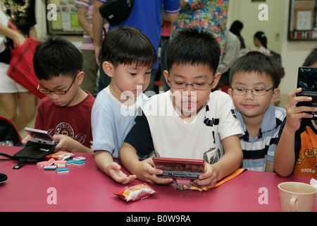 Jungs spielen Gameboy, Singapur, Südostasien Stockfoto