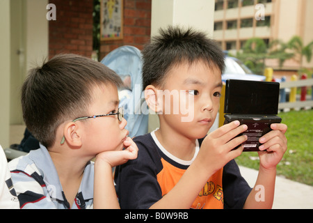 Jungs spielen Gameboy, Singapur, Südostasien Stockfoto