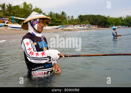Alte Fischer stehen im Meer in der Nähe von Senggigi Angeln für kleine Fische, die mit traditionellen Methoden, Insel Lombok, Lesser Sunda ich Stockfoto