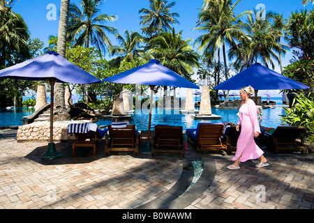 Frau auf dem Weg zum Sonnenbaden neben dem Schwimmbad des Sheraton Hotels in der Nähe von Senggigi Lombok Insel, kleinen Sunda-Inseln, Stockfoto