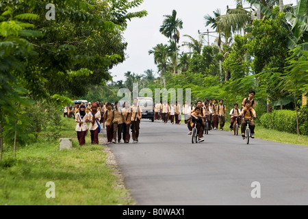 Schulkinder in Uniformen zu Fuß entlang einer Straße nach der Schule in der Nähe von Mataram, Lombok Insel, kleinen Sunda-Inseln, Indon gekleidet Stockfoto