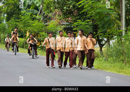 Schulkinder in Uniformen zu Fuß entlang einer Straße nach der Schule in der Nähe von Mataram, Lombok Insel, kleinen Sunda-Inseln, Indon gekleidet Stockfoto