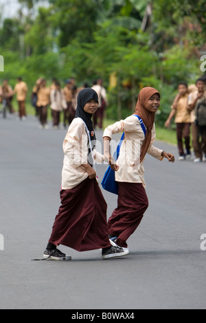 Muslimische Mädchen, Schülerinnen und Schüler ihre Uniformen zu Fuß entlang einer Straße nach der Schule in der Nähe von Mataram, Lombok Island, weniger Sonne Stockfoto