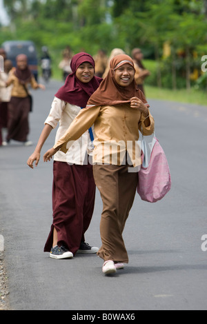 Muslimische Mädchen, Schülerinnen und Schüler ihre Uniformen zu Fuß entlang der Straße nach der Schule in der Nähe von Mataram, Lombok Island, geringerem S Stockfoto