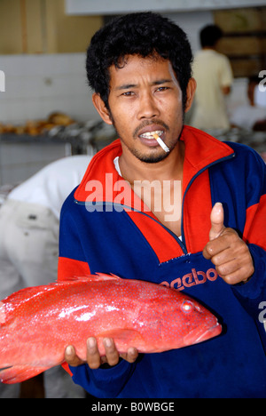 Mann Rauchen einer Zigarette, Fischverkäufer auf dem Fischmarkt in Sandakan, Sabah, Borneo, Malaysia, Südost-Asien Stockfoto