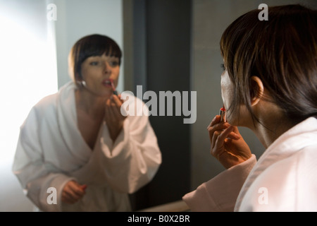 eine Frau, die Anwendung von Lipgloss im Spiegel Stockfoto