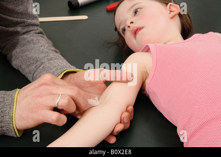 Menschliche Hände reinigen eines jungen Mädchens Arm in Vorbereitung für eine Injektion Stockfoto