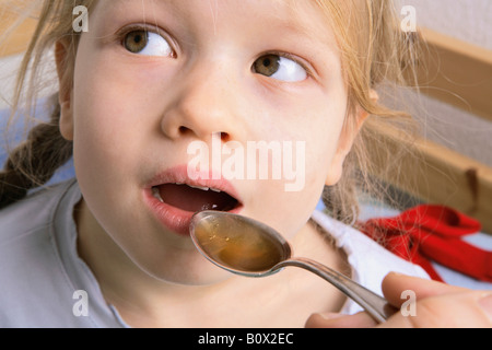 Eine menschliche Hand halten einen Löffel der Medizin für ein junges Mädchen zu schlucken Stockfoto