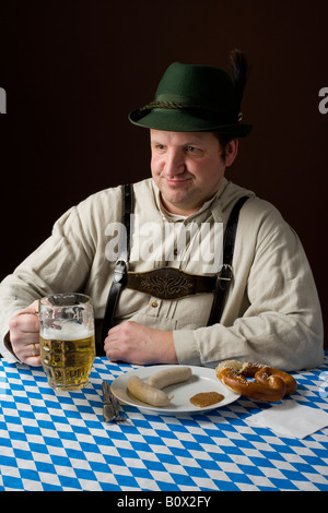 Stereotype deutscher Mann in bayrischer Tracht mit einem Bier und deutsches Essen Stockfoto