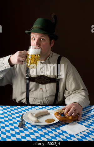 Stereotype deutscher Mann in bayrischer Tracht, trinken ein Bier und deutsches Essen Stockfoto