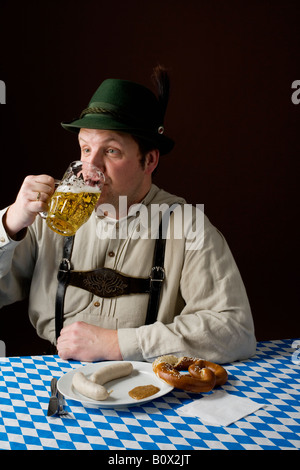 Stereotype deutscher Mann in bayrischer Tracht, trinken ein Bier und deutsches Essen Stockfoto