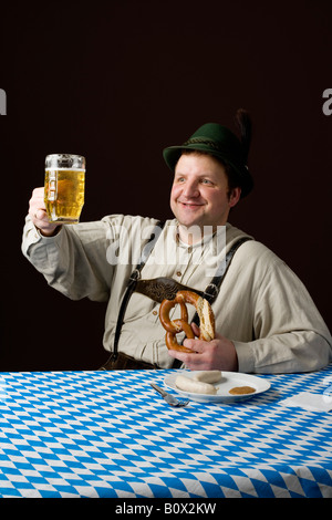 Stereotype Deutsch Mann rösten ein Glas Bier und eine Brezel zu halten Stockfoto