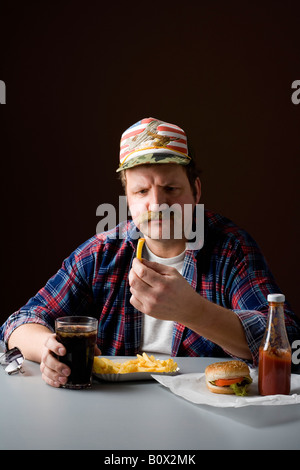 Stereotype amerikanischer Mann hält eine Pommes-Frites und starrte es Stockfoto