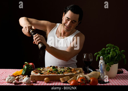 Stereotypen Italiener mit einer Pfeffermühle auf seine pizza Stockfoto