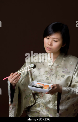 Eine Frau, gekleidet in einem Kimono Sushi-Essen Stockfoto