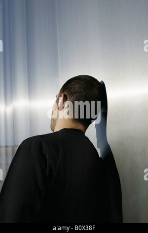 Ein Mann gegen eine Wand gelehnt Stockfoto
