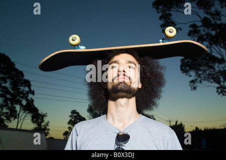 Ein Mann, eine Skateboard auf dem Kopf balancieren Stockfoto