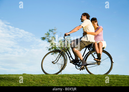 Ein Mann reitet ein Fahrrad und eine junge Frau sitzt auf der Rückseite Stockfoto