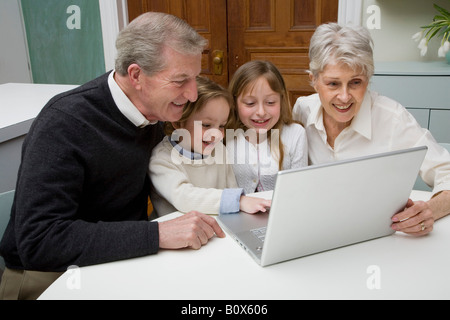 Enkel mit einem Laptop, während ihre Großeltern zu sehen Stockfoto