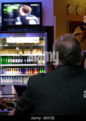 Älterer Mann schaut Fußball auf einem Fernsehgerät in einem Café am Flughafen, Vereinigtes Königreich, Birmingham Stockfoto