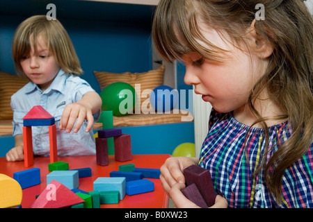 Jungen (8-9) und Mädchen (6-7) spielen mit bauen von Backsteinen, Porträt Stockfoto