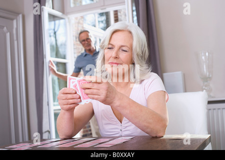Ältere Frau bei Solitaire, senior Mann im Hintergrund, Porträt Stockfoto