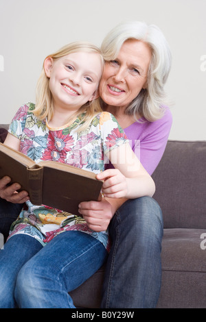 Großmutter und Granddaugher (8-9) Lesung buchen auf Sofa, Porträt Stockfoto