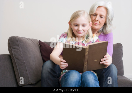 Großmutter und Enkelin (8-9) Lesung buchen auf Sofa, Porträt Stockfoto