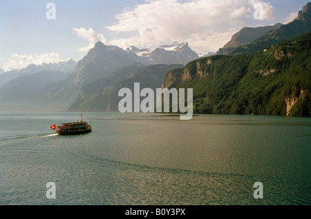 Fähre auf dem Alpensee, Vierwaldstättersee Schweiz mit Schnee auf den Bergen, von Brunnen nach Seelisberg. Schweizer Flagge auf der Fähre flattern im Wind. Stockfoto