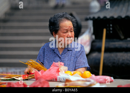 Eine ältere Frau bereitet sich auf leichte Weihrauch auf einem öffentlichen buddhistischen Schrein auf Kowloon Stockfoto