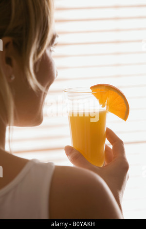 Blonde Frau hält ein Glas Orangensaft, Rückansicht Stockfoto