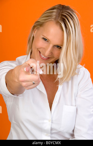 Junge, blonde Frau zeigt auf etwas Stockfoto