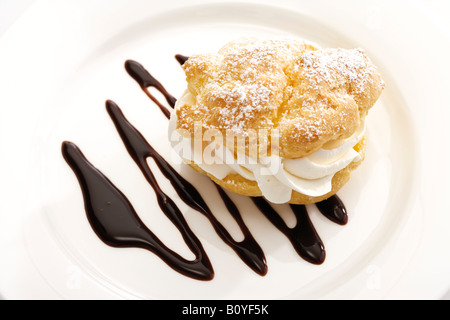 Windbeutel mit Schoko Sauce auf Teller Stockfoto