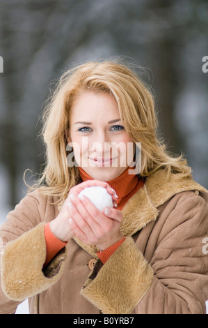 Österreich, Salzburger Land, Altenmarkt, junge Frau mit einem Schneeball, Lächeln, Porträt Stockfoto