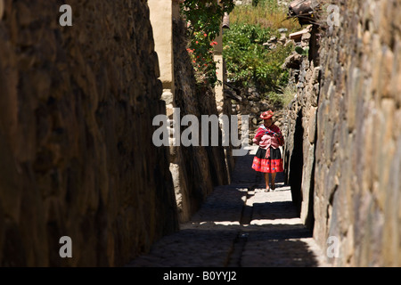 Einheimische Frau zu Fuß entlang einer schmalen Straße in Ollantaytambo im Heiligen Tal der Inkas Peru Stockfoto