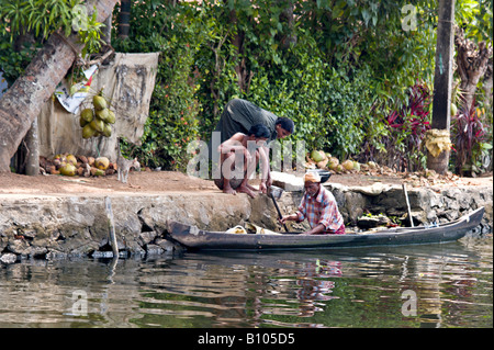 Indien KERALA indischen Ehepaar Fisch vom örtlichen Fischer, der seinem Kanu entlang der Grachten von Haus zu Haus Zeilen kaufen Stockfoto