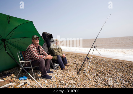 UK England Suffolk Aldeburgh zwei Männer Meeresangeln vom Strand in der Sonne Stockfoto