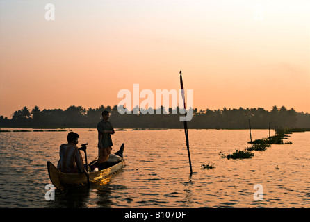 Indien KERALA zwei indische Fischer Rudern ihre Holzboot in Vembanad See bei Sonnenuntergang, wie sie sich vorgenommen, das Nachtangeln zu verbringen Stockfoto