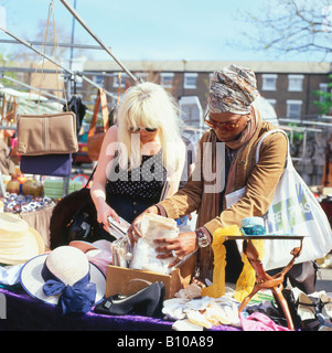 Zwei junge Frauen suchen durch Kleid nähen Muster auf einem Greenwich vintage Markt in London England UK KATHY DEWITT Abschaltdruck Stockfoto