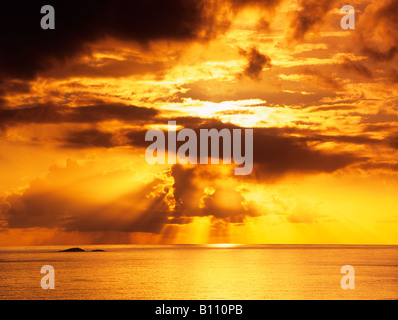 Atemberaubende dramatische Golden orange Sonnenuntergang mit Wolken und orange Sonne über ruhigen Meer Ozean auf der schottischen Westküste im Herbst. Schottland Großbritannien Großbritannien Stockfoto