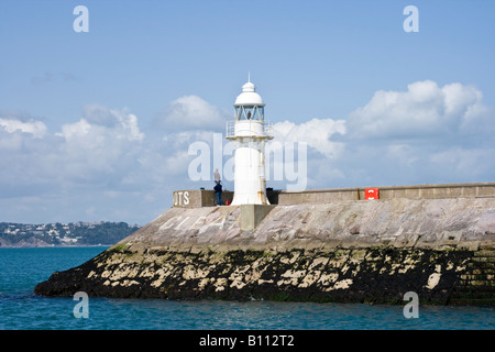 Leuchtturm am Eingang zum Hafen von Brixham mit Torquay im Hintergrund Stockfoto