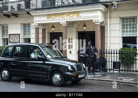 Zwei Polizisten tauchen aus Browns Hotel, Mayfair London England UK ein schwarzes Taxi vorbei Stockfoto