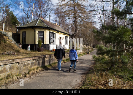 dh Cambus O May ROYAL DEESIDE ABERDEENSHIRE Paar zu Fuß am alten Bahnhof vorbeilaufen Menschen Wanderer in schottland wandern im Hochland Stockfoto