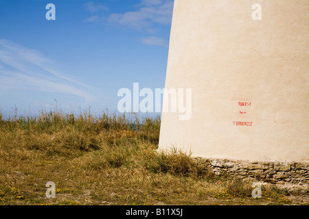 Graffiti auf dem Torre Nueve - der Neue Turm - ein alter Aussichtsturm und Verteidigungsturm am Ufer von El Palmar lautet "TURIST YOU AR TERRORIST". Playa de El Palmar, El Palmar, Vejer de la Frontera, Cádiz, Andalucía, Spanien. Stockfoto