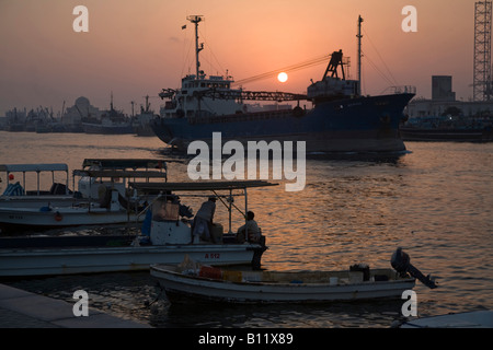 Sharjah Corniche in der Nacht mit dem Sonnenuntergang und plätschert das Wasser mit Booten und Schiffen in den vorderen und hinteren Boden Stockfoto