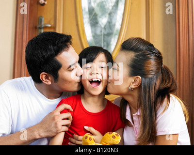 Eltern, die ihre Tochter küssen Stockfoto