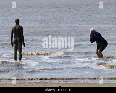 Antony Gormley geschnitzte Figur am Strand bei Crosby durch Besucher, Liverpool, Merseyside, England, UK fotografiert werden, Stockfoto