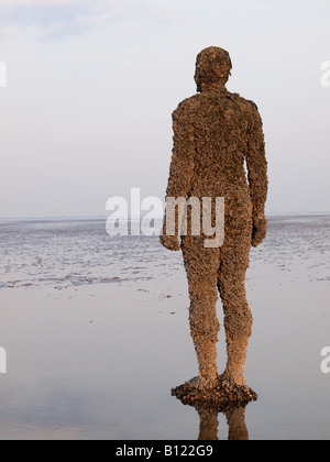 Antony Gormley geschnitzte Figur am Strand bei Crosby, Liverpool, Merseyside, England, Vereinigtes Königreich, Stockfoto